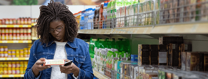 femme lisant une étiquette dans un rayon de supermarché