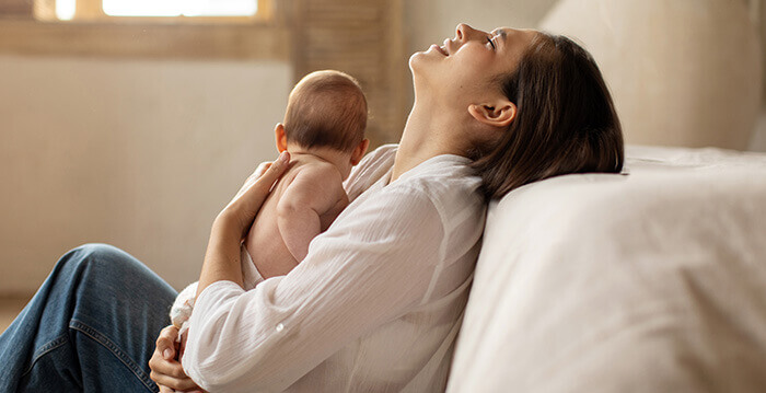 jeune mère exténuée tenant son bébé dans les bras