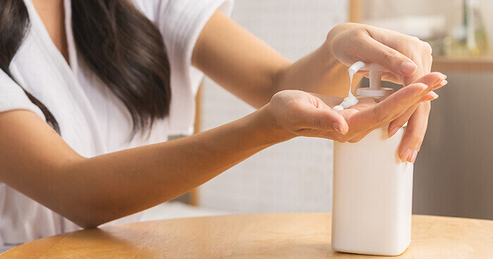 femme qui prélève de la crème hydratante dans un flacon-pompe