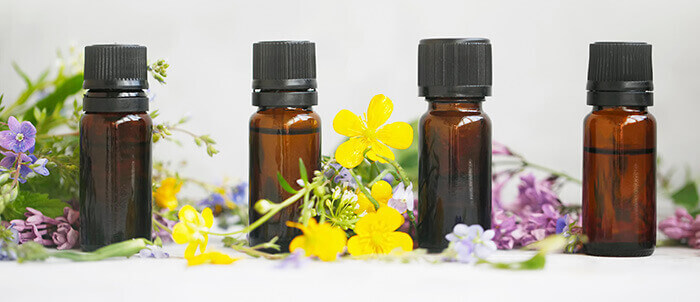 assortiment de flacons d'huiles essentielles entourés de fleurs