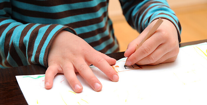 paln sur les mains d'un enfant gaucher en train de dessiner