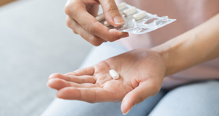 gros plan sur les mains d'une femme prenant un médicament sous forme de comprimé