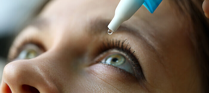 femme s'instillant une goutte de lubrifiant oculaire dans l'oeil