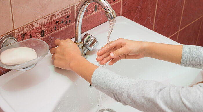 femme se lavant les mains avec de l'eau et du savon