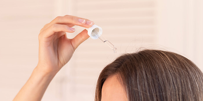femme s'appliquant un sérum capillaire sur les cheveux