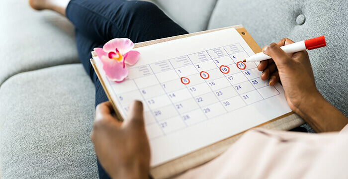 femme entourant en rouge les jours de son cycle menstruel sur un calendrier