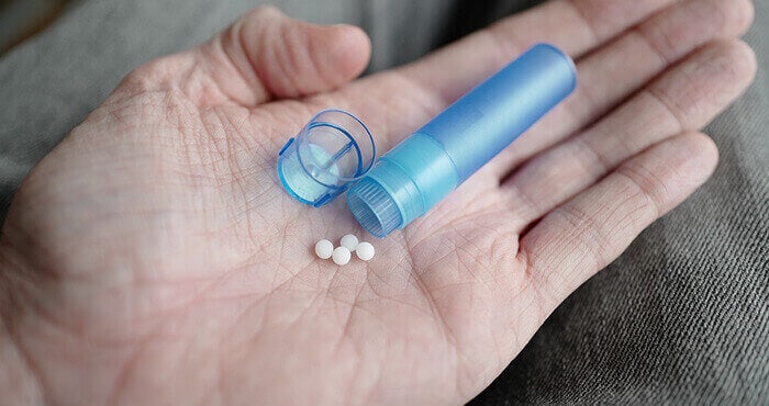 granules homéopathiques tenue dans la main d'un homme