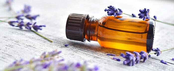 flacon d'huile essentielle de lavande entouré de fleurs de lavande