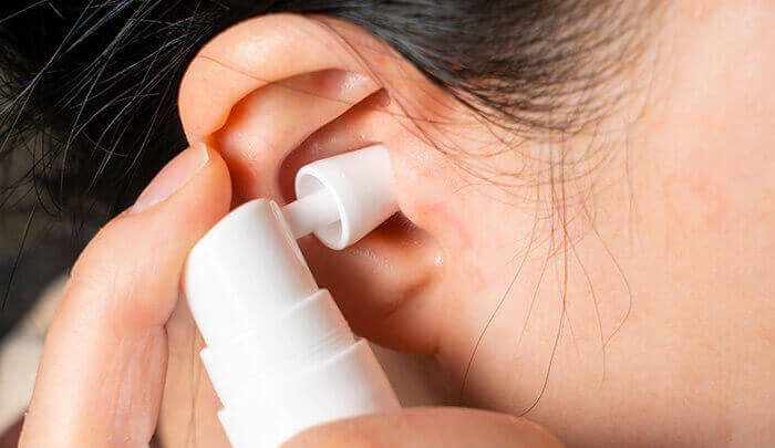 Spray nettoyant appliqué dans une oreille