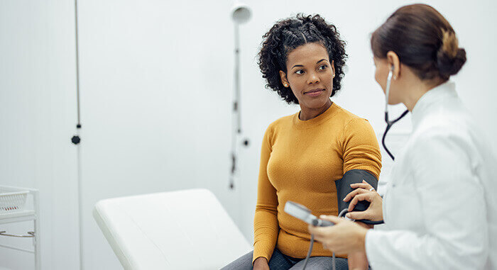 Médecin prenant la tension d'une patiente au cours d'une consultation médicale