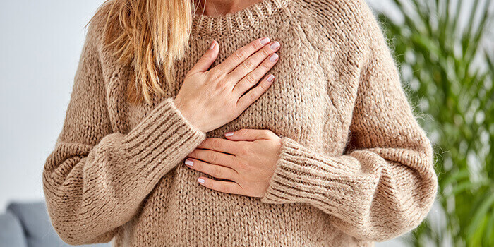 plan sur les mains d'une femme se tenant la poitrine au niveau du coeur