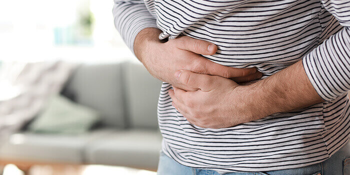 gros plan sur un homme se tenant le ventre de douleur suite à une intoxication alimentaire