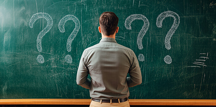 homme de dos face à un tableau noir avec de grands points d'interrogation
