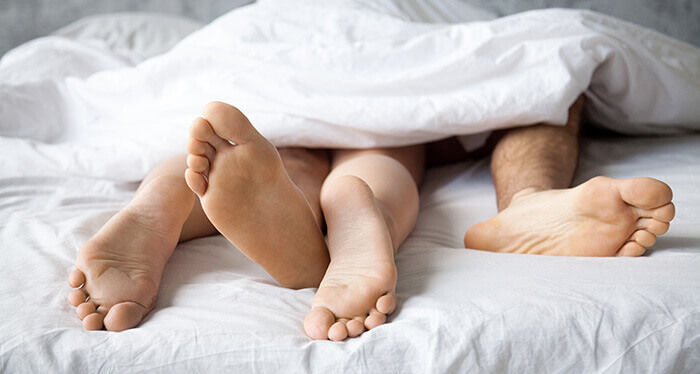 focus sue les pieds d'un couple dépassant de sous une couette