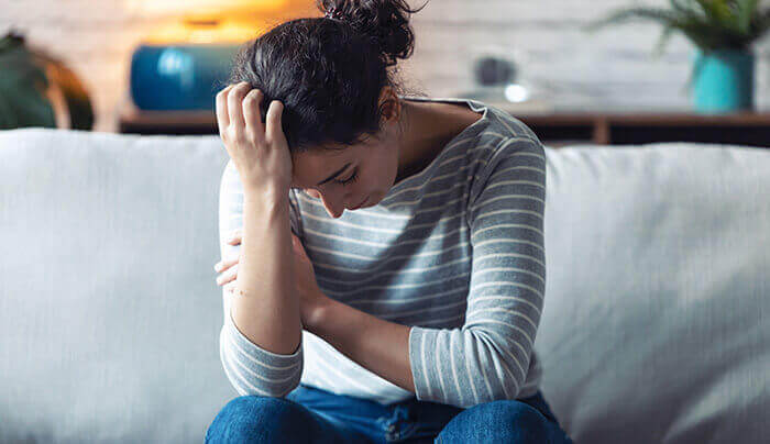 femme dépressive recourbée sur un canapé