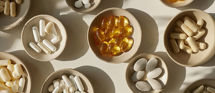 gélules et comprimés de compléments alimentaires dans des petits bols