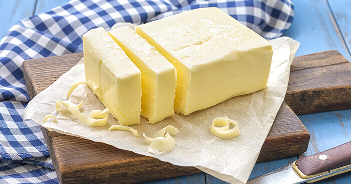 Motte de beurre présentée sur une planchette de bois et une nappe à carreaux