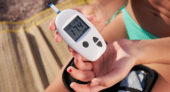 plan sur le lecteur de glycémie d'une femme diabétique controllant sa glycémie à la plage