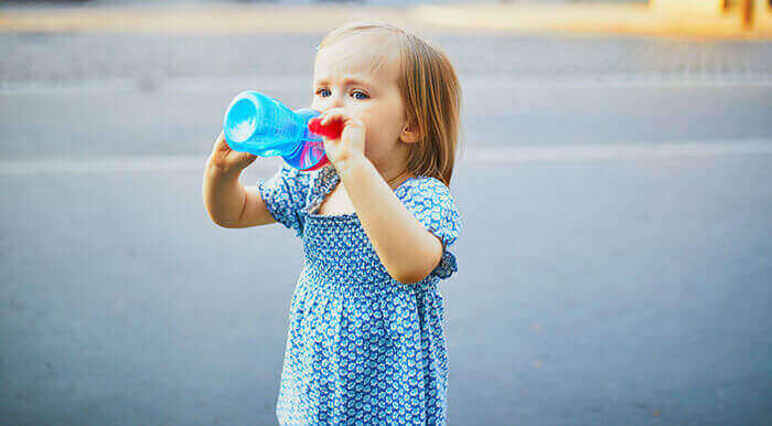 petite fille en train de boire de l'eau dans une gourde d'enfant