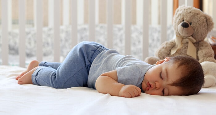 bébé qui dort paisiblement sur le ventre dans son lit