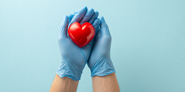 mains gantées portant un coeur