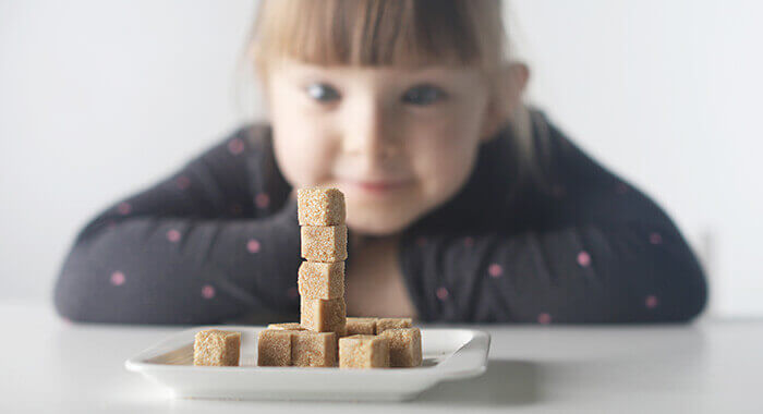 filette regardant attentivement une pile de carrés de sucre en équilibre