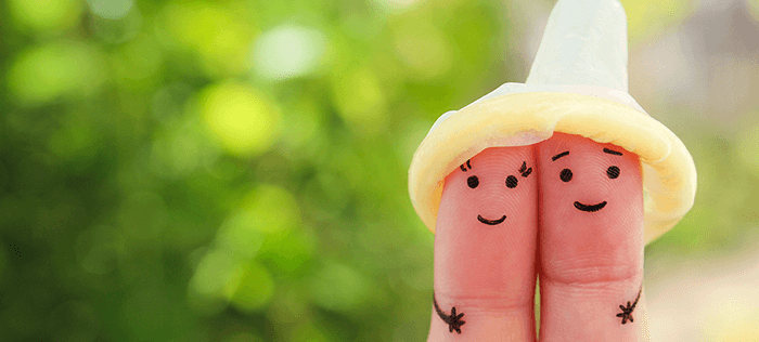 deux doigts de main couverts d'un préservatif représentant un couple
