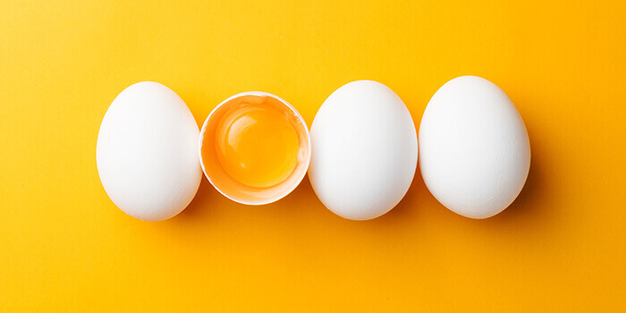 4 oeufs dont 1 cassé sur fond jaune