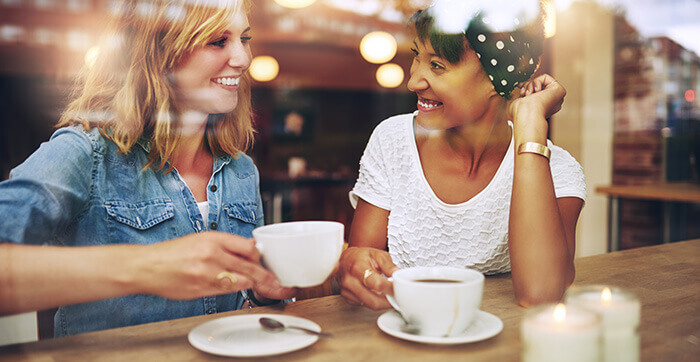 2 amies riant en buvant un café