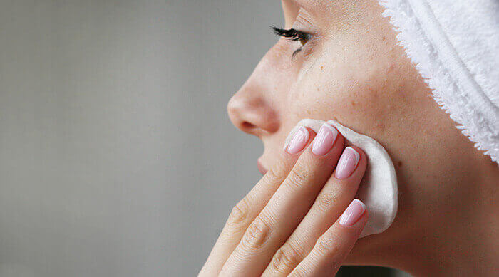 femme appliquant un soin à l'aide d'un coton sur une peau acnéique