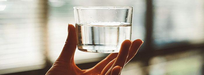 verre d'eau tenu dans une main