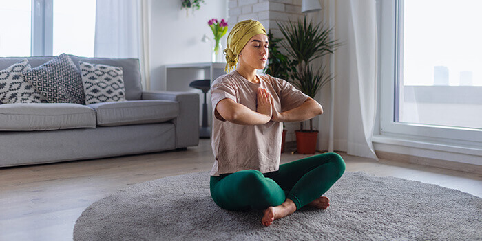 femme souffrant d'un cancer pratiquant le yoga dans son salon