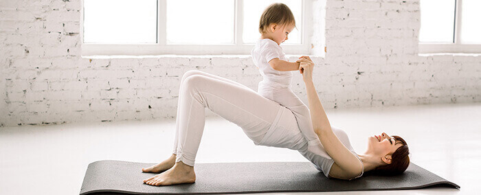 femme en train de faire des abdos avec son bébé sur le ventre