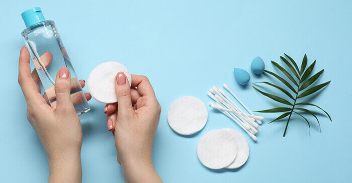 flacon de lotion tonique avec des disques de coton sur un fond bleu