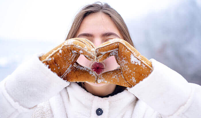 femme faisant un coeur avec des moufles en hiver