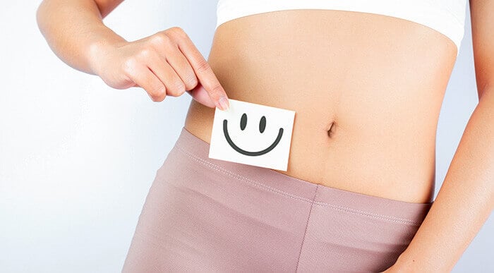 femme qui tient un petit carton avec un sourire devant son ventre