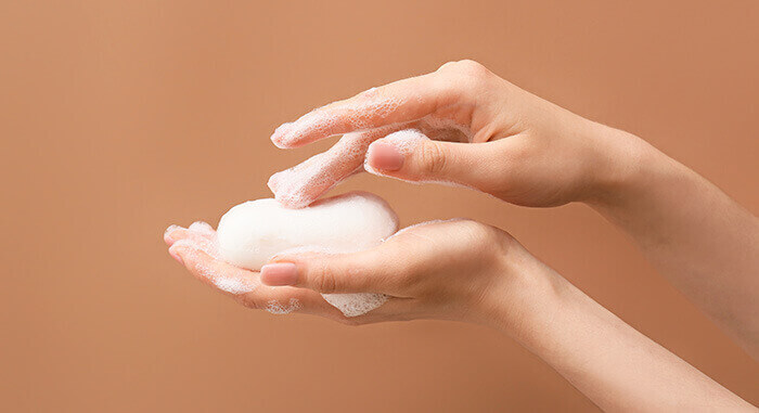 plan sur des mains pleines de mousse tenant un pain de savon