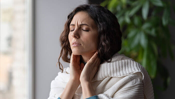 femme souffrant d'un mal de gorge, se tatant la gorge