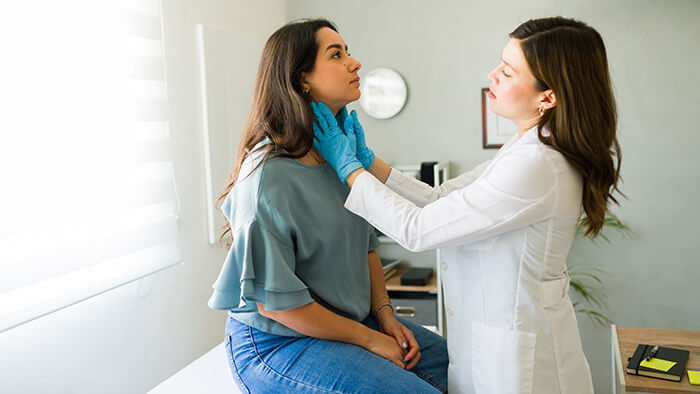 femme en consultation médicale avec la médecin qui lui tâte la gorge