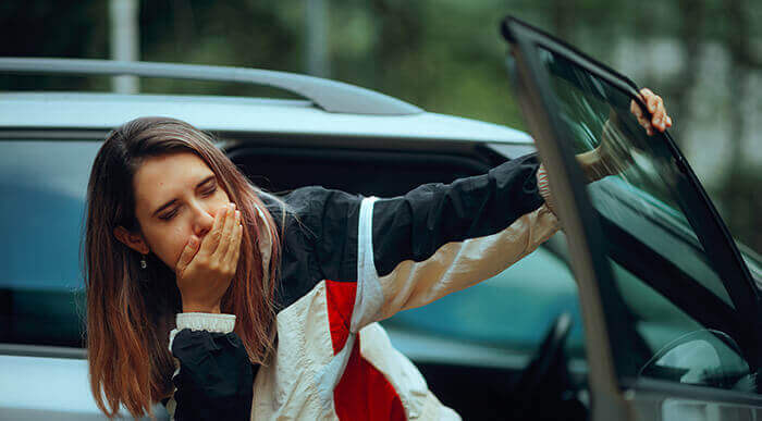 femme prise de nausée à la sortie d'une voiture