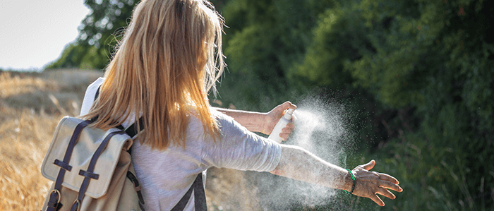 femme s'aspergant de répulsif anti-tique