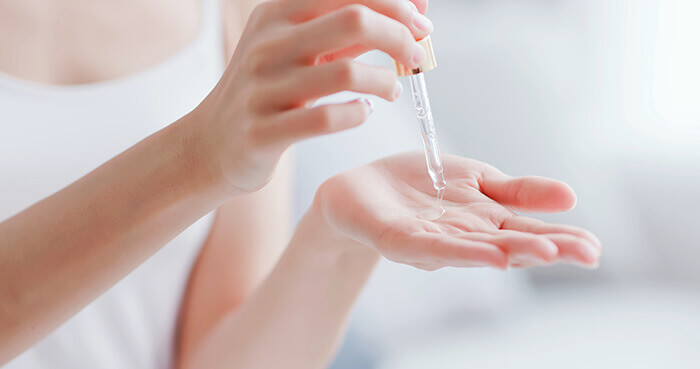 femme prélevant quelques gouttes de sérum dans la main dans le cadre de son soin du visage quotidien