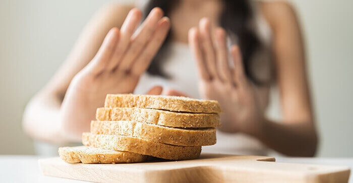 femme faisant non avec les mains à des tranches de pain posées en premier plan