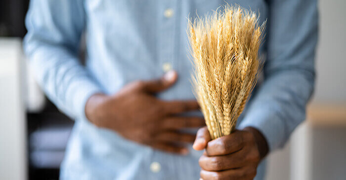 homme souffrant de douleurs abdominales et tenant une gerbe de blé à la main