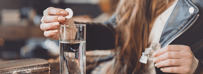 femme mettant un médicament dans un verre d'eau