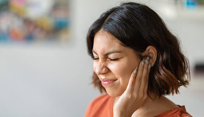 femme souffrant de misophonie, se tenant l'oreille en grimaçant