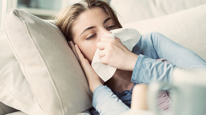 jeune femme malade en train de se moucher