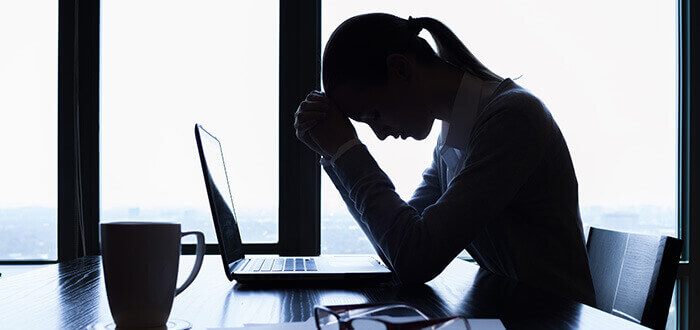 femme stressée se tenant la tête entre les mains au bureau