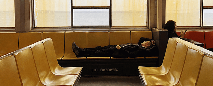 homme en costume dormant sur la banquette d'un transport en commun