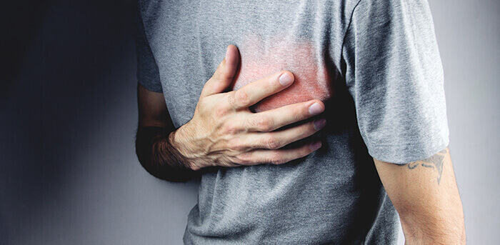 homme se tenant la poitrine à cause d'une douleur